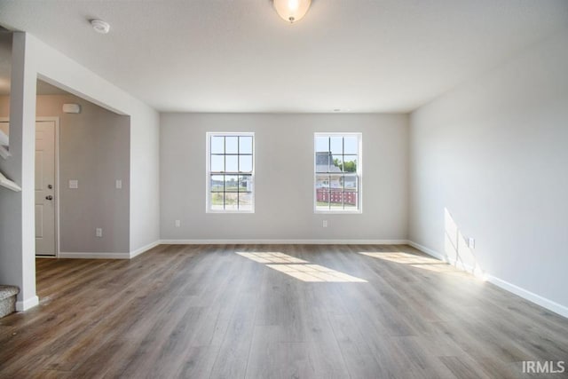 empty room with stairway, wood finished floors, and baseboards