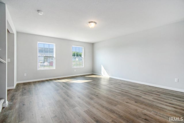 spare room featuring baseboards and dark wood finished floors