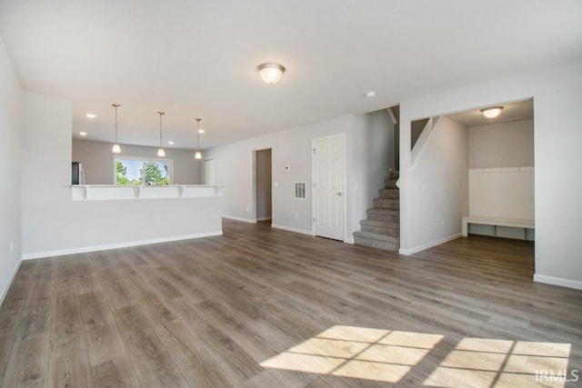 unfurnished living room with recessed lighting, stairway, baseboards, and wood finished floors