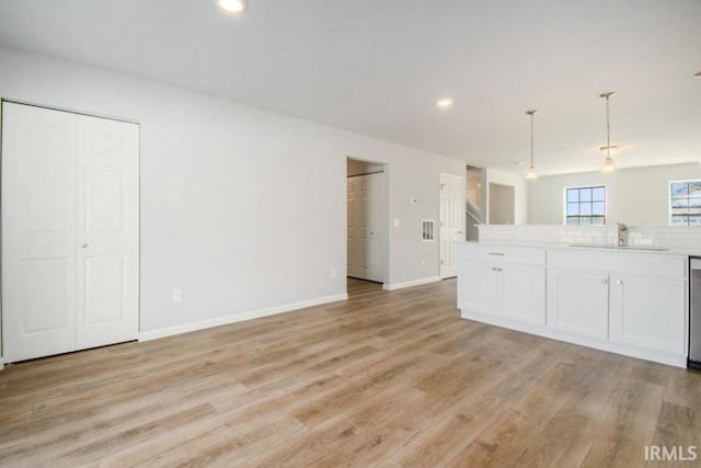 kitchen with light wood-type flooring, light countertops, a sink, and baseboards