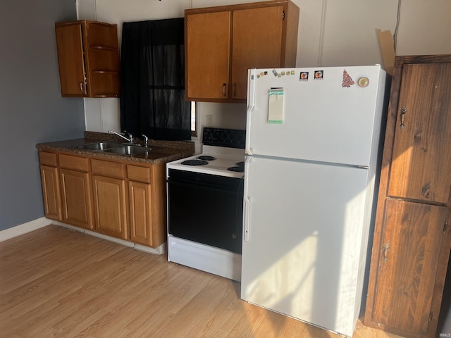 kitchen with range with electric cooktop, brown cabinetry, freestanding refrigerator, light wood-style floors, and a sink