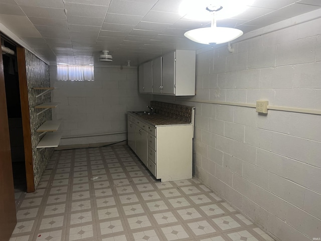 interior space with concrete block wall, light floors, and a sink