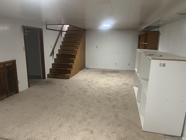 finished below grade area featuring stairs, visible vents, and carpet flooring