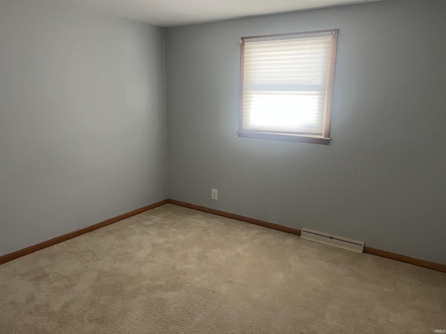 spare room featuring light carpet, visible vents, and baseboards