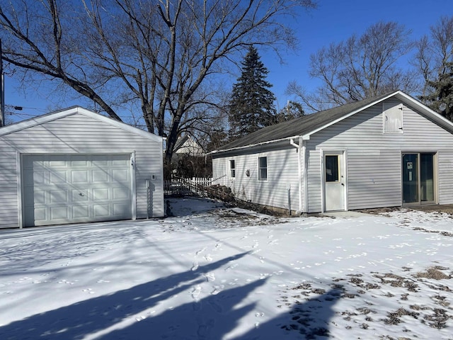 snow covered property featuring an outdoor structure and a detached garage