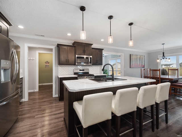 kitchen with dark brown cabinetry, stainless steel appliances, a sink, visible vents, and decorative backsplash