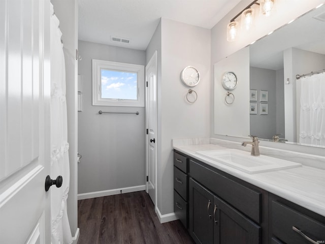 full bath with baseboards, visible vents, wood finished floors, and vanity