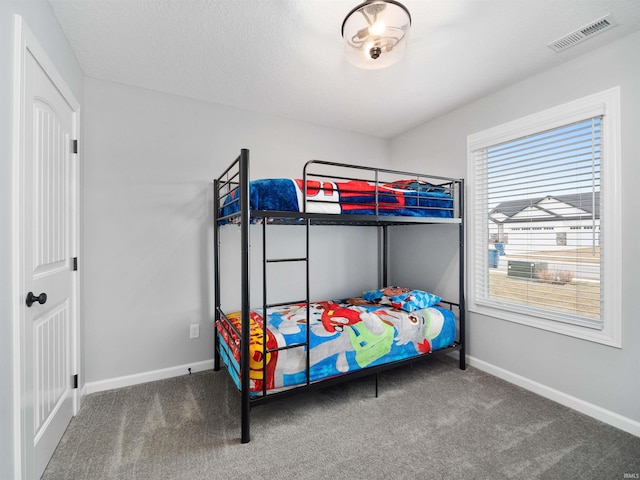 carpeted bedroom with visible vents, a textured ceiling, and baseboards