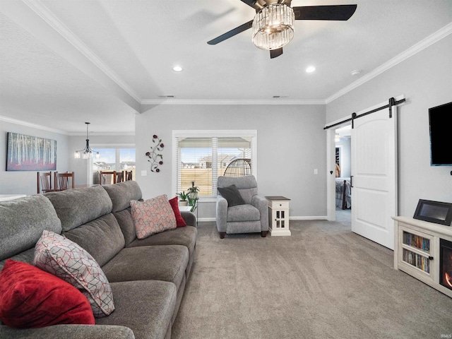 living room featuring a barn door, baseboards, light colored carpet, ornamental molding, and ceiling fan with notable chandelier