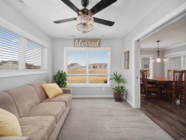 living area with baseboards, visible vents, and a ceiling fan