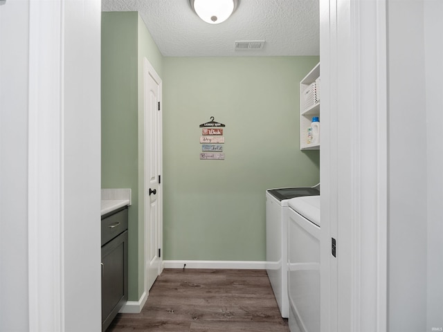 clothes washing area featuring a textured ceiling, laundry area, visible vents, washer and dryer, and dark wood-style floors