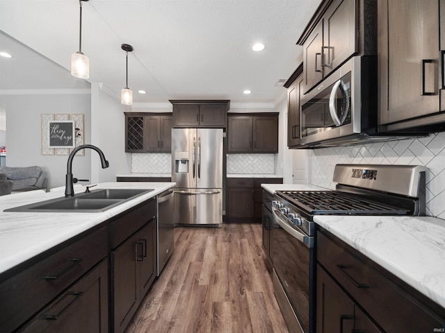 kitchen with hanging light fixtures, appliances with stainless steel finishes, a sink, dark brown cabinets, and wood finished floors