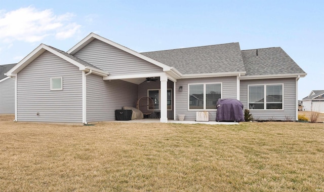 rear view of property with a patio, roof with shingles, a lawn, and a ceiling fan