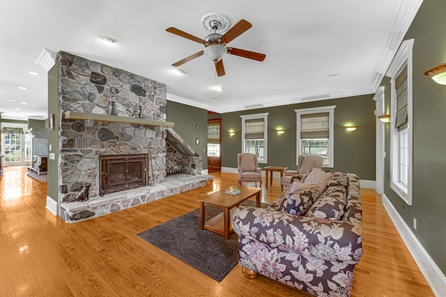 living room with crown molding, a healthy amount of sunlight, a fireplace, and wood finished floors