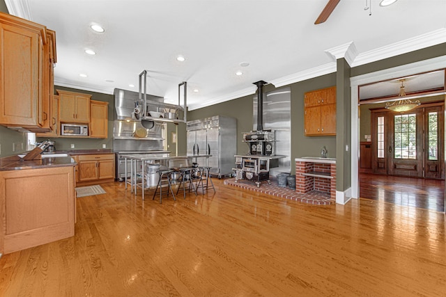 kitchen with stainless steel appliances, recessed lighting, light wood-style flooring, ornamental molding, and a ceiling fan