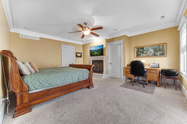 bedroom featuring visible vents, a glass covered fireplace, ceiling fan, crown molding, and carpet floors