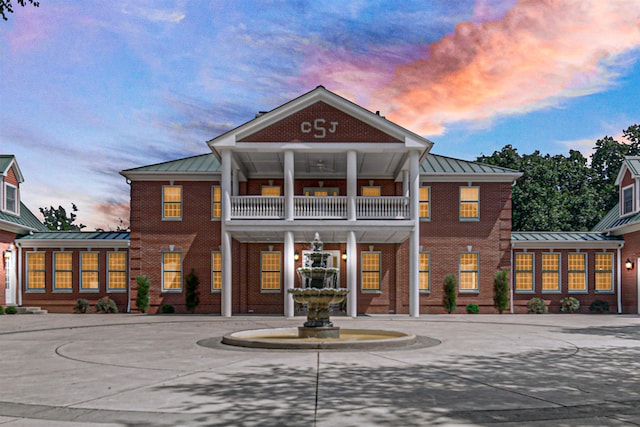 view of front of property featuring a standing seam roof, brick siding, metal roof, and curved driveway