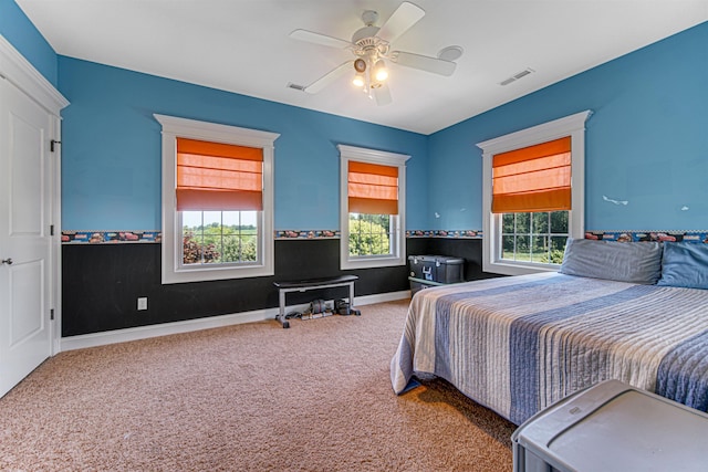 carpeted bedroom with ceiling fan, multiple windows, visible vents, and baseboards