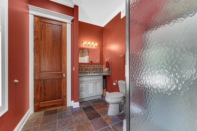 bathroom with stone tile floors, baseboards, toilet, ornamental molding, and vanity