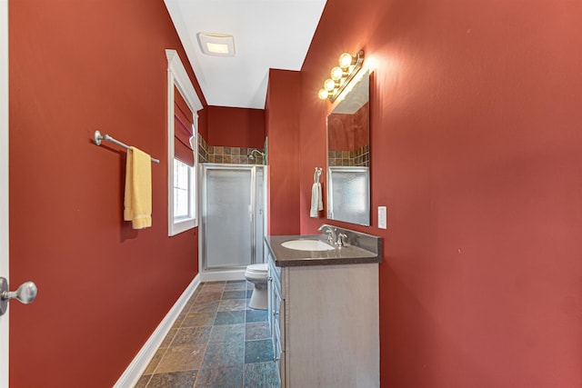 bathroom featuring a stall shower, baseboards, toilet, stone finish floor, and vanity