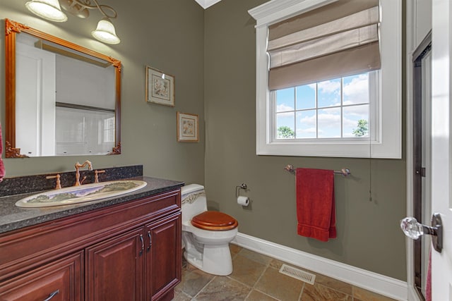 bathroom featuring toilet, vanity, visible vents, and baseboards