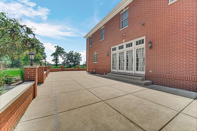 rear view of house with entry steps, brick siding, and a patio area