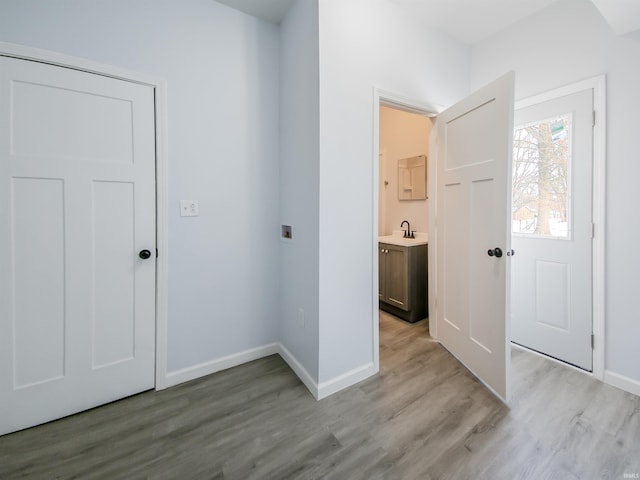 interior space featuring light wood-type flooring, a sink, and baseboards