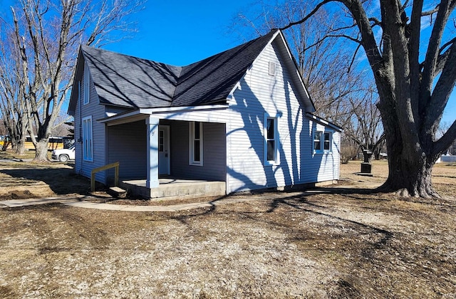 view of side of property featuring covered porch and a shingled roof