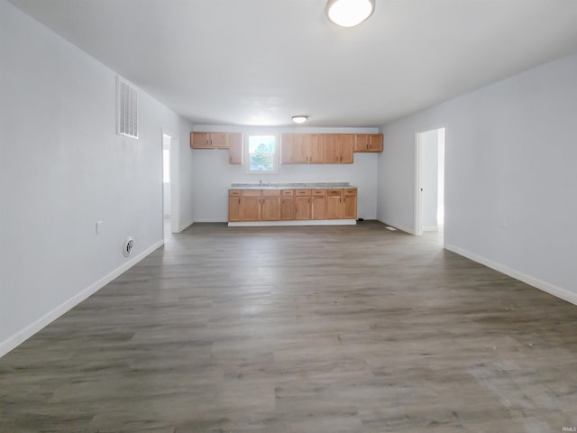 kitchen with baseboards, visible vents, open floor plan, wood finished floors, and light countertops