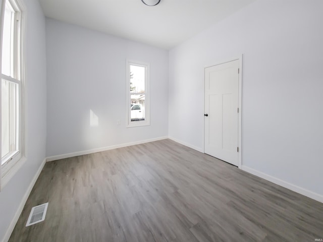 empty room featuring wood finished floors, visible vents, and baseboards