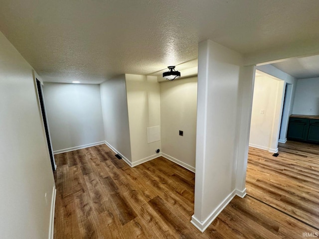 corridor with a textured ceiling, wood finished floors, and baseboards