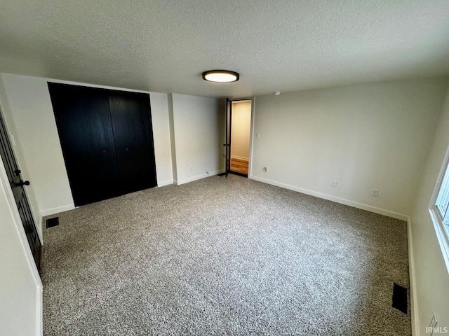 unfurnished bedroom featuring a textured ceiling, carpet flooring, visible vents, and baseboards