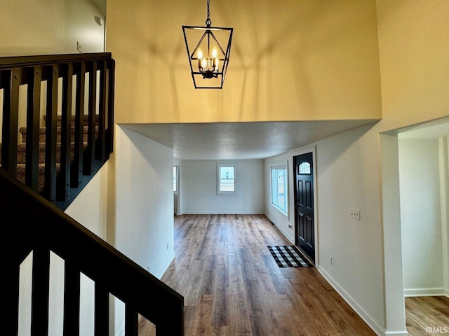 foyer entrance with a chandelier, stairway, baseboards, and wood finished floors