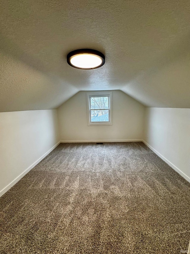 bonus room with carpet floors, vaulted ceiling, a textured ceiling, and baseboards