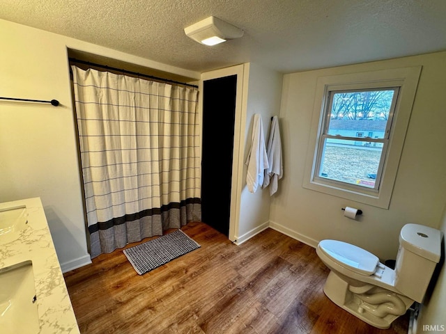 full bathroom featuring baseboards, a textured ceiling, toilet, and wood finished floors