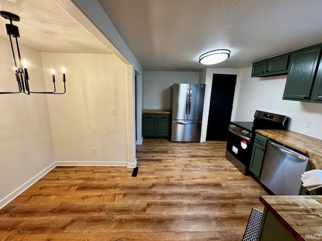 kitchen with light wood finished floors, wood counters, stainless steel appliances, and green cabinetry