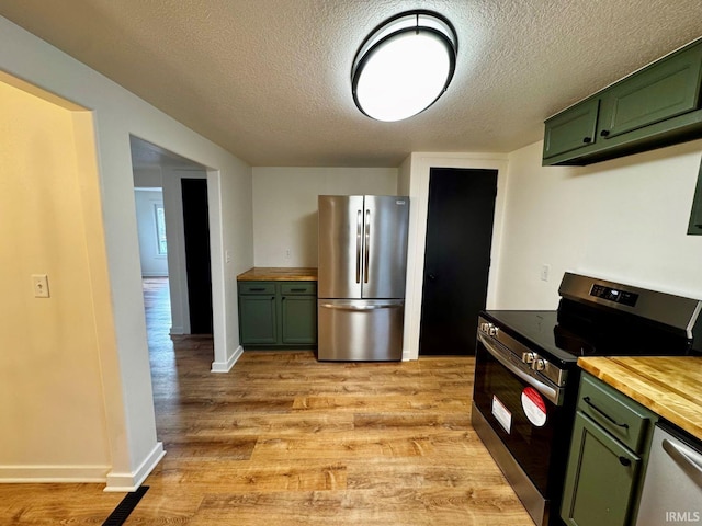 kitchen with green cabinets, appliances with stainless steel finishes, light wood-type flooring, and wood counters