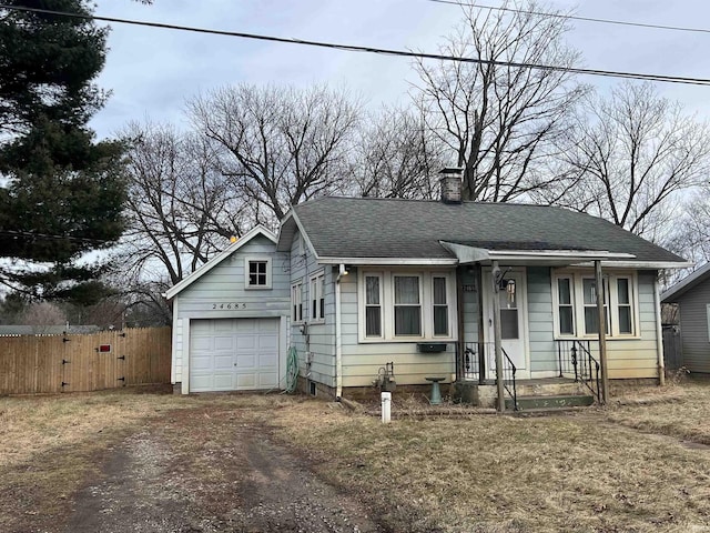 view of front of house featuring a chimney, a shingled roof, fence, a garage, and driveway