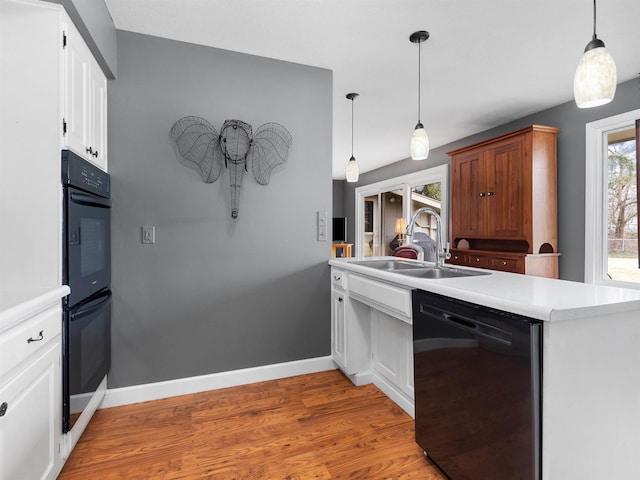 kitchen featuring baseboards, light wood-style floors, light countertops, black appliances, and a sink