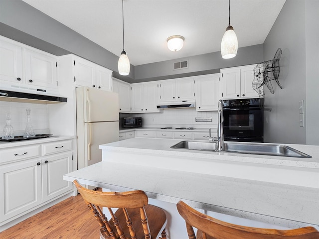 kitchen with tasteful backsplash, visible vents, under cabinet range hood, and black appliances