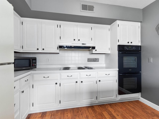 kitchen featuring under cabinet range hood, visible vents, white cabinets, light countertops, and black appliances