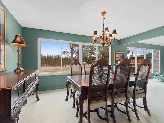 carpeted dining room featuring a notable chandelier and baseboards