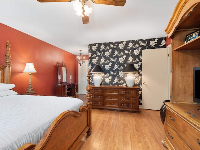 bedroom with light wood-style floors and ceiling fan with notable chandelier