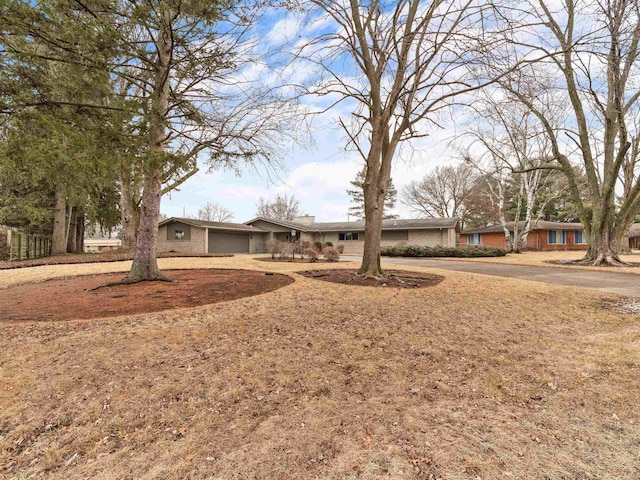 ranch-style house with driveway, brick siding, and an attached garage