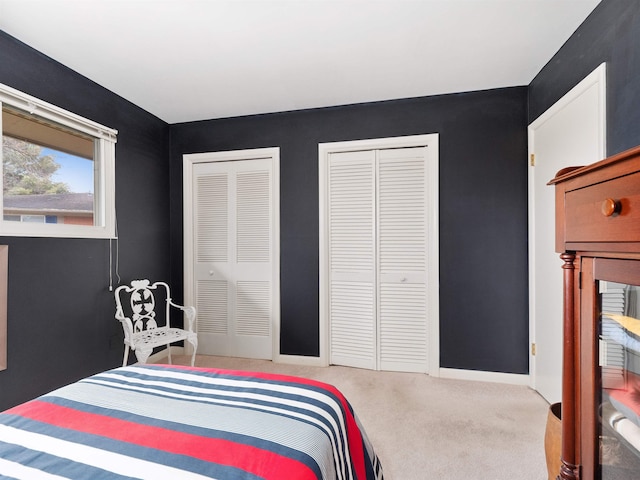 bedroom with baseboards, carpet, and multiple closets