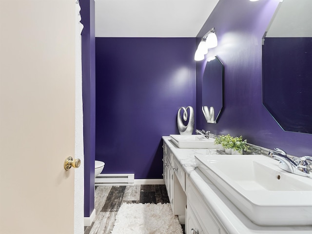 bathroom featuring a baseboard heating unit, a sink, toilet, and wood finished floors