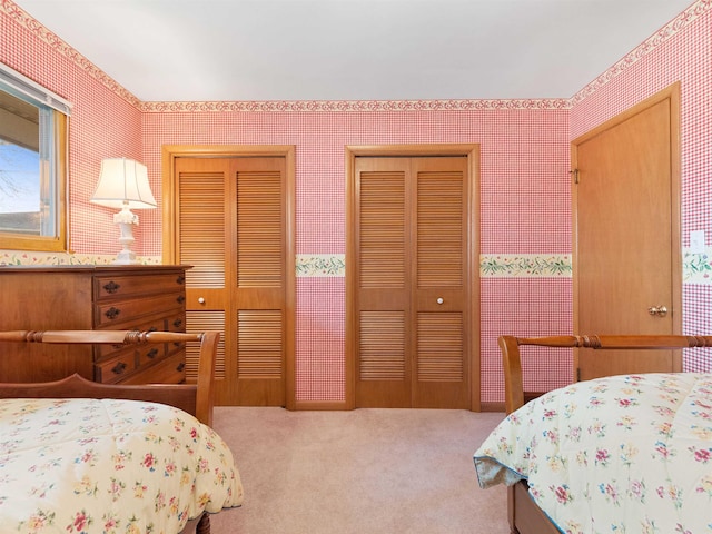 carpeted bedroom with wallpapered walls and multiple closets