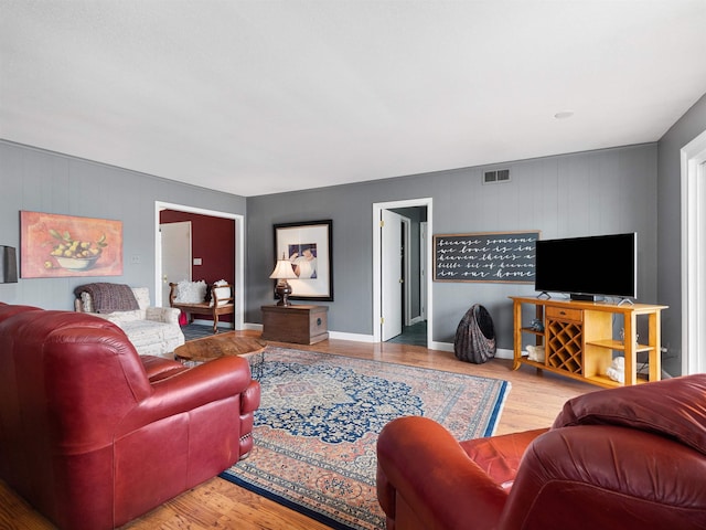 living area with baseboards, visible vents, and wood finished floors