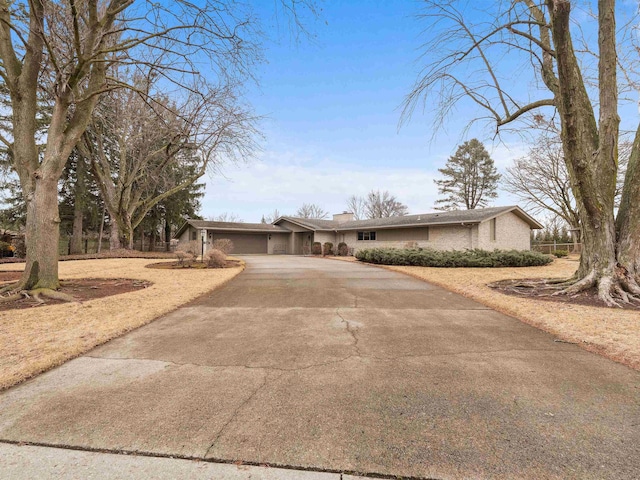 view of front of house featuring driveway, a chimney, and an attached garage