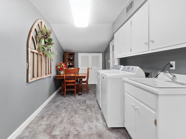 washroom featuring a sink, visible vents, baseboards, cabinet space, and washer and clothes dryer